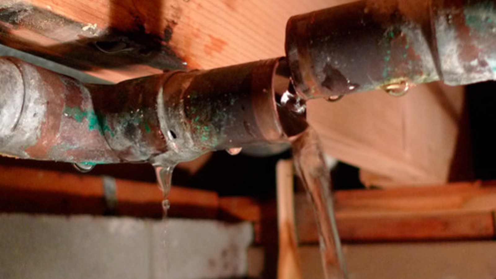 Water dripping from a damaged copper pipe inside a home